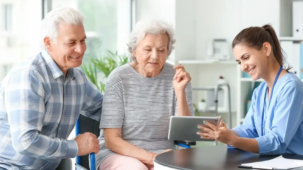 Professional home caregiver offering support to an elderly client in a comfortable living room