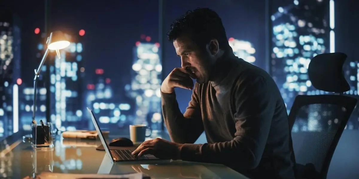 An aging business owner sitting at a desk contemplating exit strategy options for his small business.