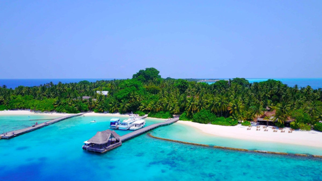 Aerial view of a tropical Caribbean resort island surrounded by crystal-clear turquoise ocean water and palm trees.