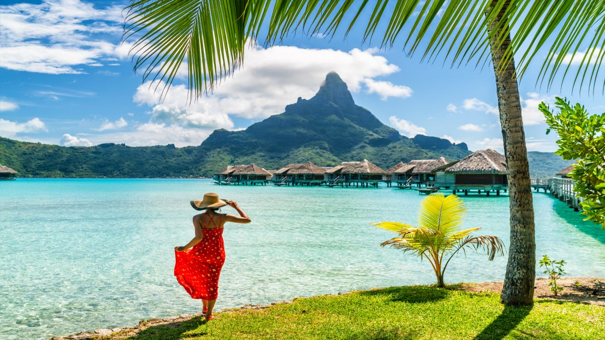 Traditional overwater bungalows in a calm lagoon with Mount Otemanu in the background in French Polynesia.