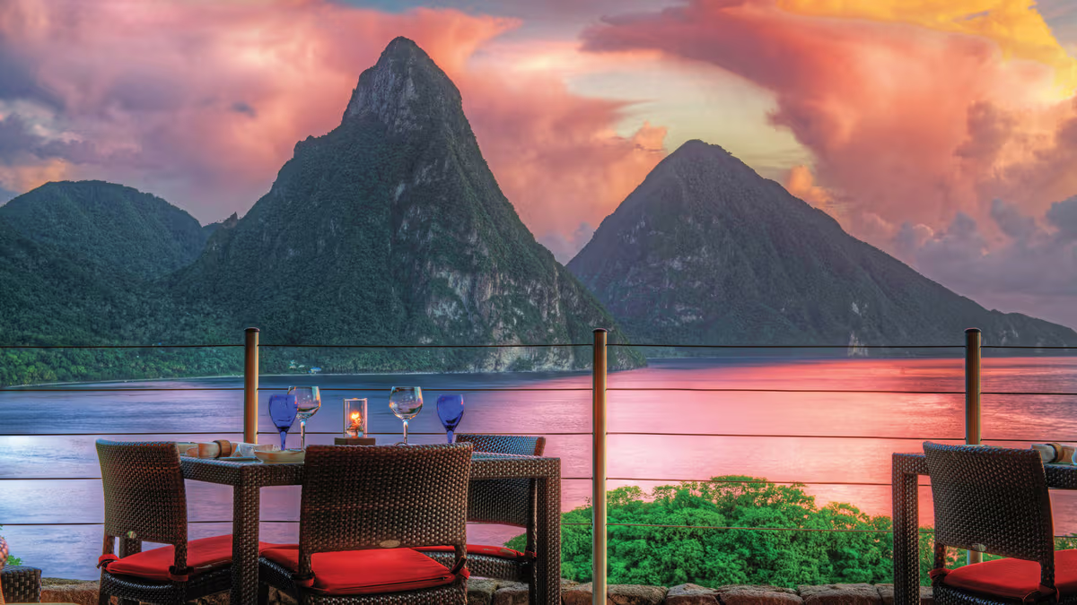 Open-air luxury resort infinity pool overlooking the green Piton mountains and ocean in St. Lucia.