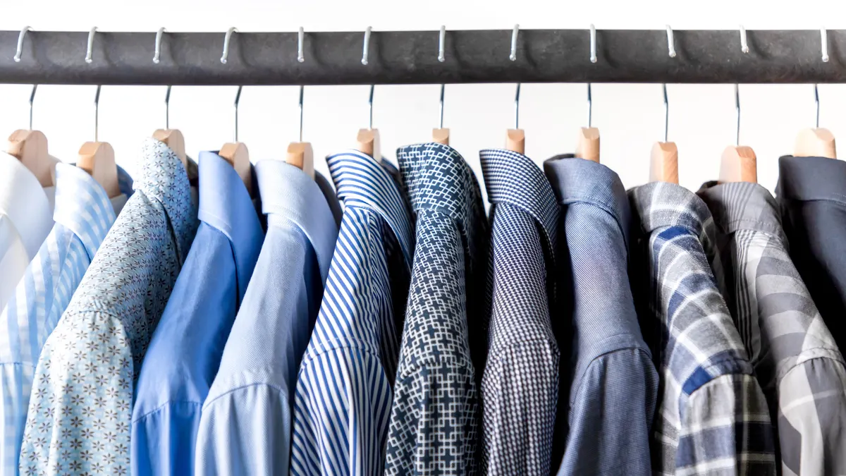 Row of neatly hung blue and patterned dress shirts