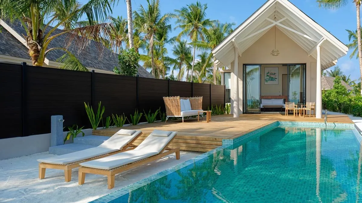 wo-story overwater luxury villas with wooden sun decks and private plunge pools extending into clear turquoise water.