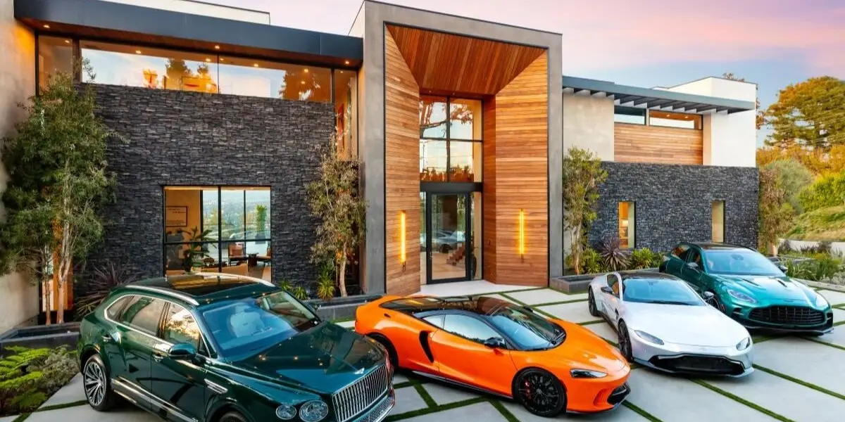 A fleet of high-performance supercars and luxury SUVs parked outside a modern architectural mansion