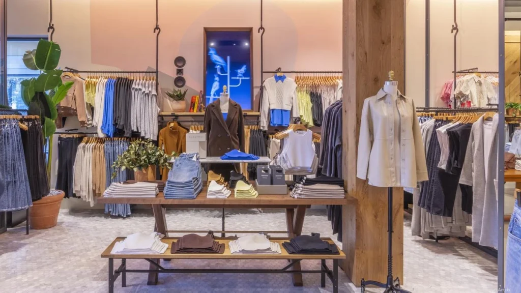 Aritzia boutique interior featuring minimalist wooden accents, warm lighting, and neatly arranged racks of clothing.