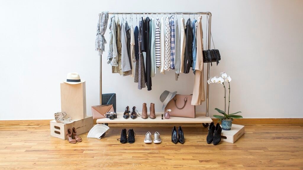 A minimalist luxury capsule wardrobe with neutral-colored blazers, soft knits, and a structured leather handbag hanging neatly.