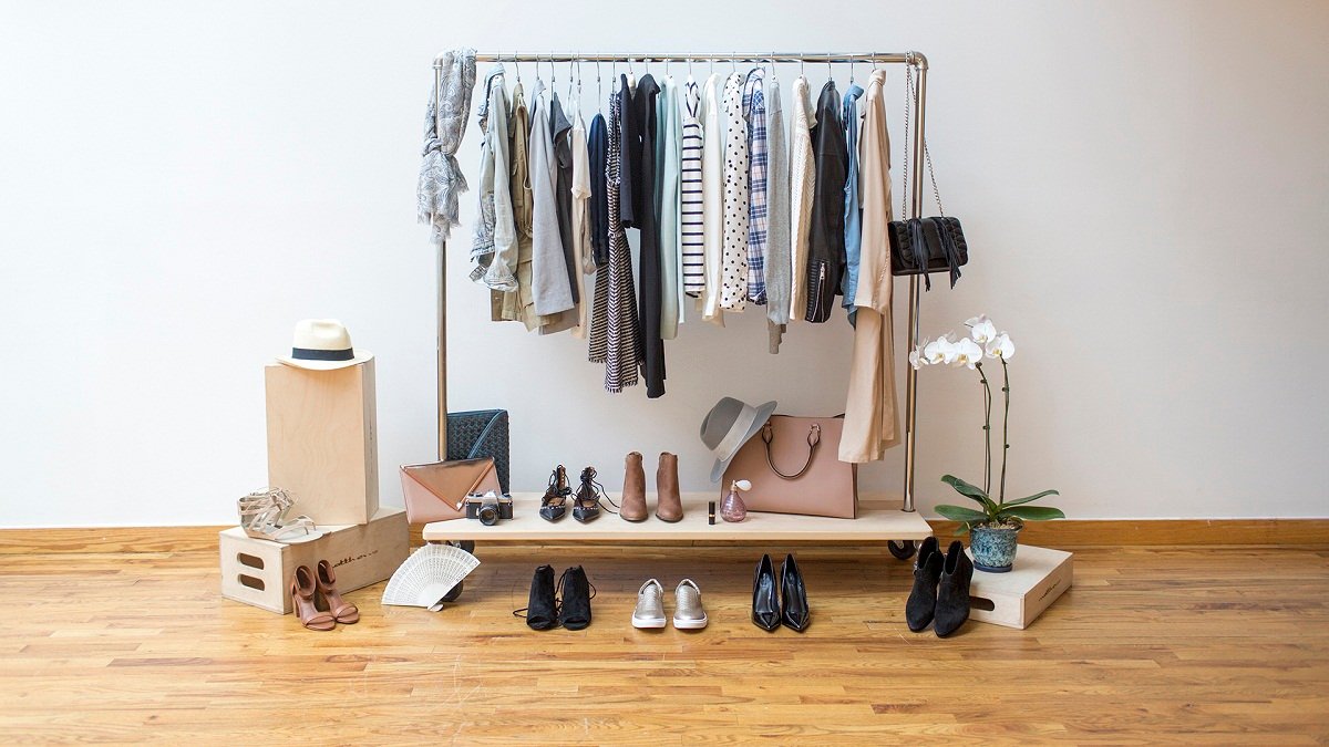 A minimalist luxury capsule wardrobe with neutral-colored blazers, soft knits, and a structured leather handbag hanging neatly.