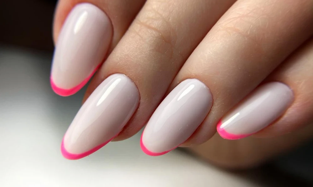 Almond-shaped neutral base nails detailed with clean, vibrant hot-pink painted tips
