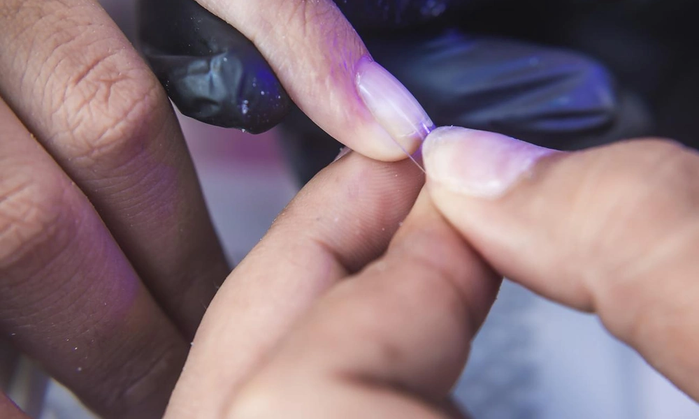 Nail technician attaching a soft-gel tip using gel adhesive during a gel x nails session