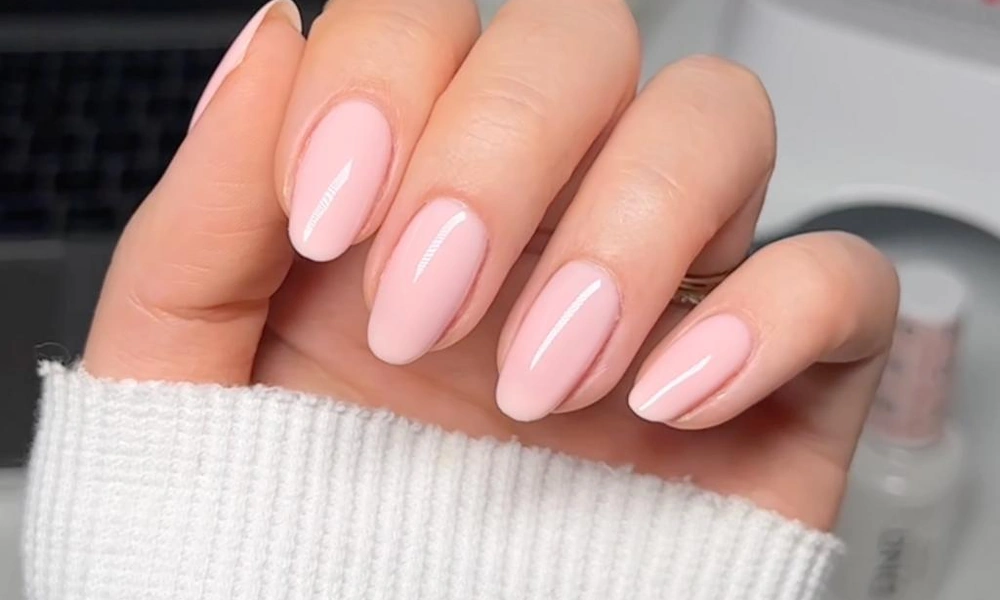 Glossy translucent light pink polish finished on neat oval-shaped natural tips