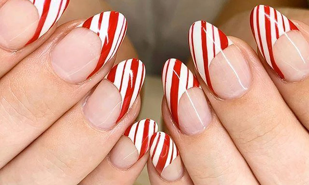 Red and white candy cane Christmas French tip nails on almond-shaped extensions