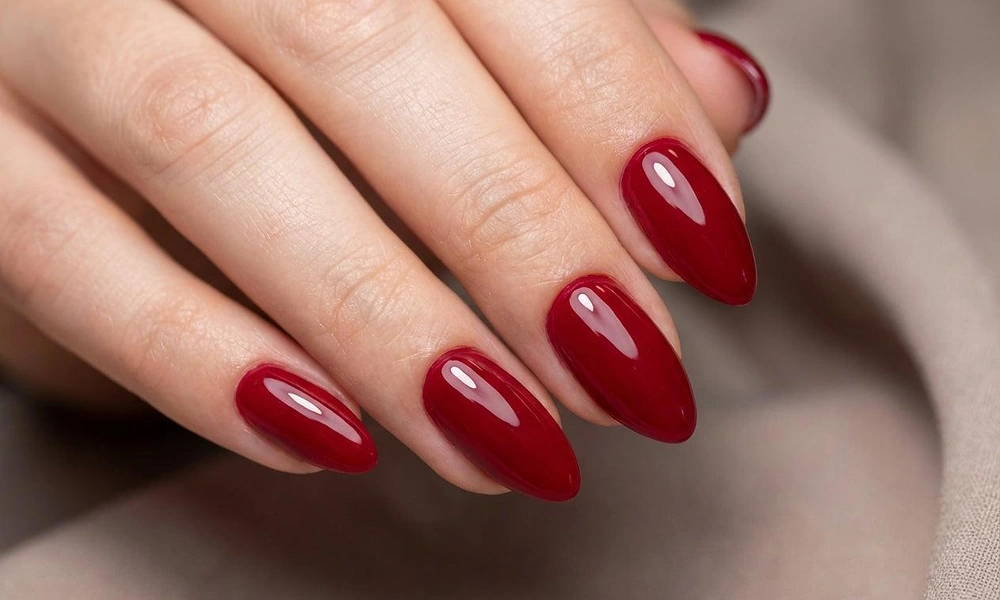 Glossy classic red Christmas nails styled in an elegant almond shape for the holiday season