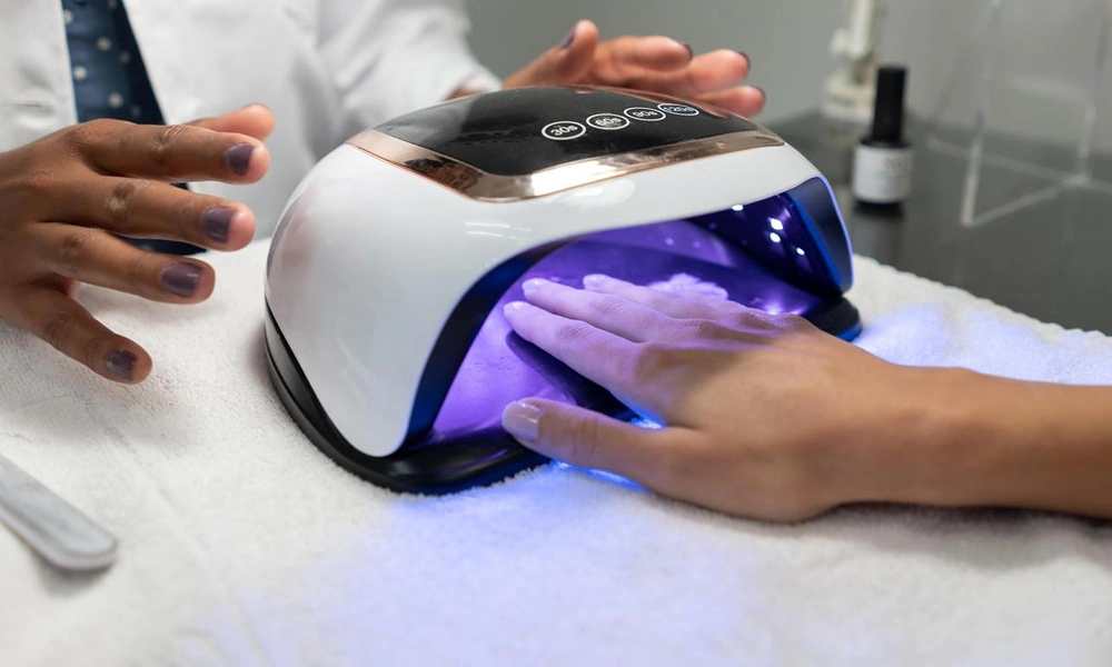 Client curing gel x nails under a professional UV and LED nail lamp