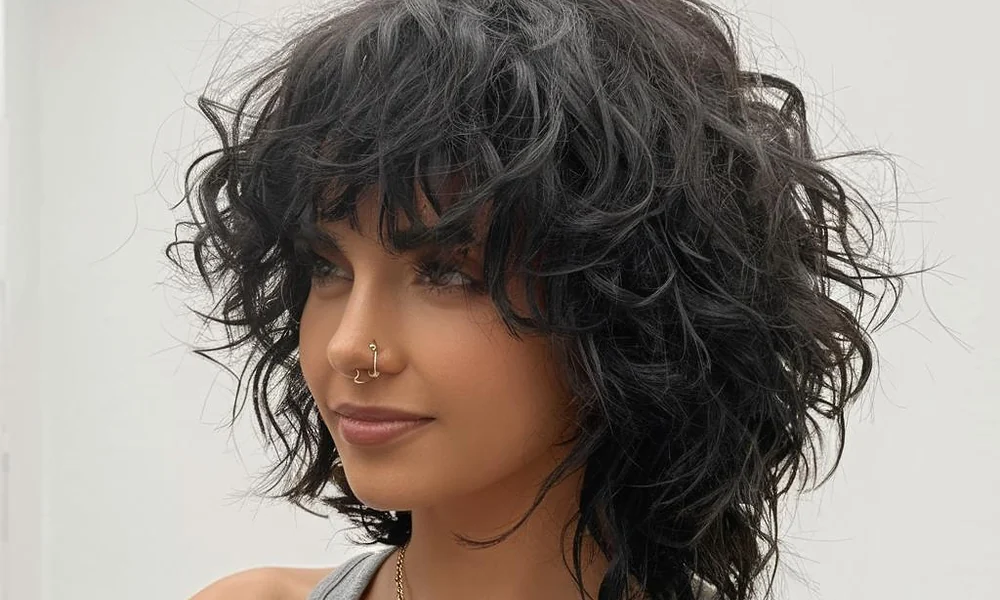 An edgy, layered curly wolf cut showing heavy crown volume and textured ends