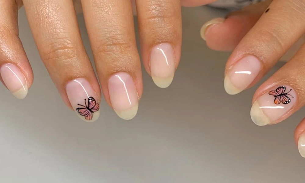 Sheer natural base polish featuring tiny detailed pink butterfly illustrations on accent fingers-Cute Nail Ideas
