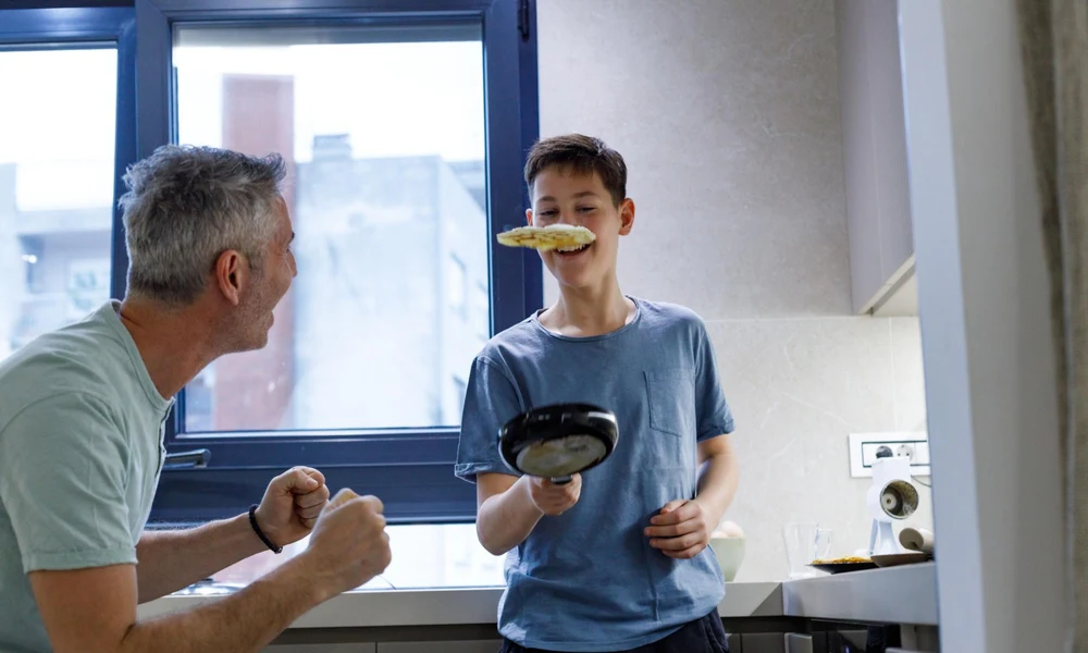 A happy father with his son while cooking breakfast together in the kitchen.