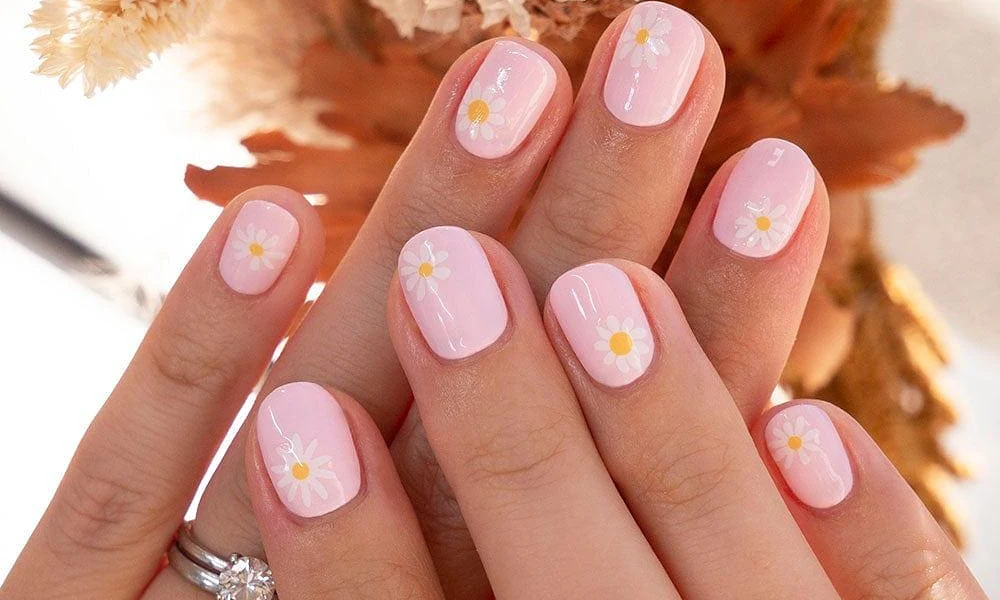 Short pastel pink tips decorated with hand-painted white and yellow daisy petals