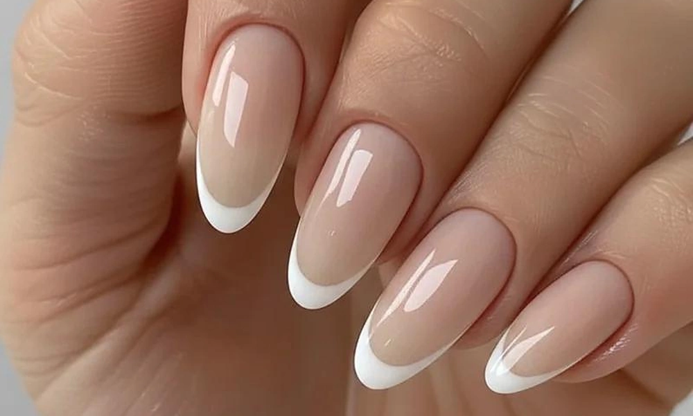Almond-shaped nude base nails detailed with clean white arched tip borders