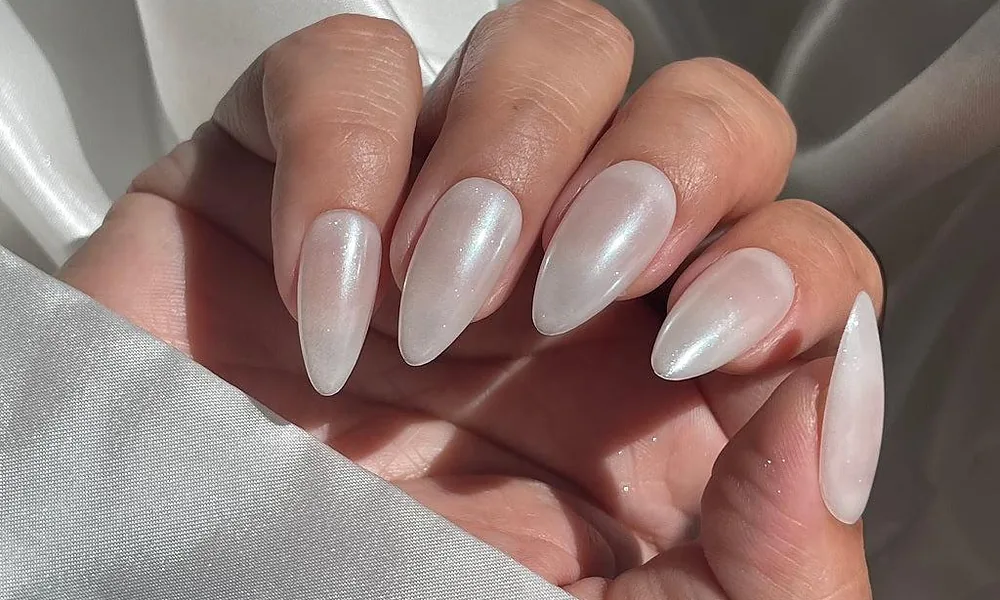 Almond-shaped milky tips featuring a glossy, pearlescent chrome glow reflecting soft light
