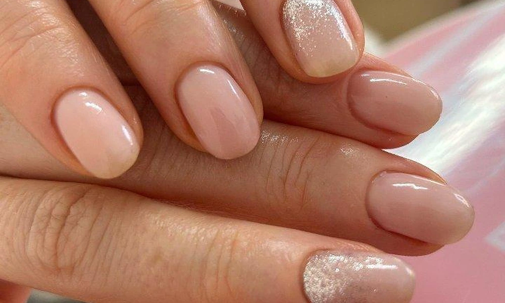 Soft beige gel polish accented with fine silver glitter dust along the cuticle line