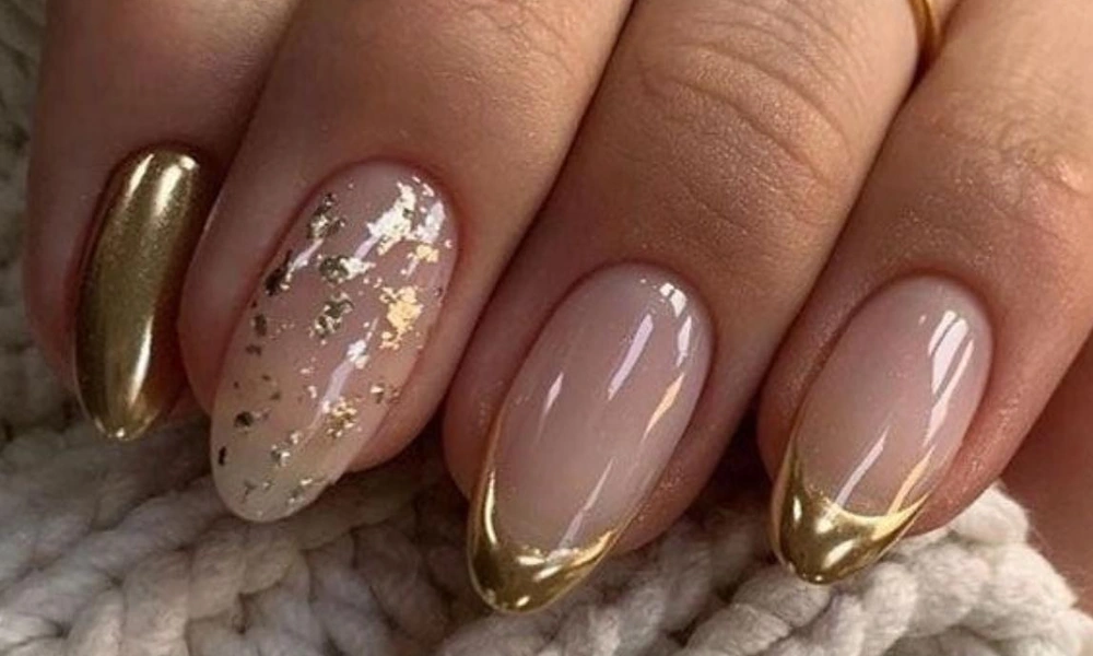 Elegant gold Christmas nails featuring metallic chrome French tips and gold foil accent details