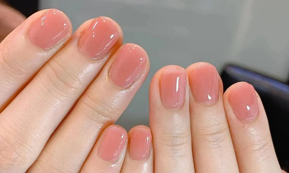 Short natural square tips coated with a translucent candy-like glossy pink gel polish