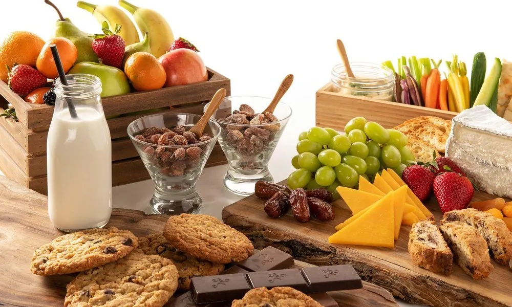 A colorful kid-friendly snack board filled with fruits, cookies, cheese, and milk-puns for kids