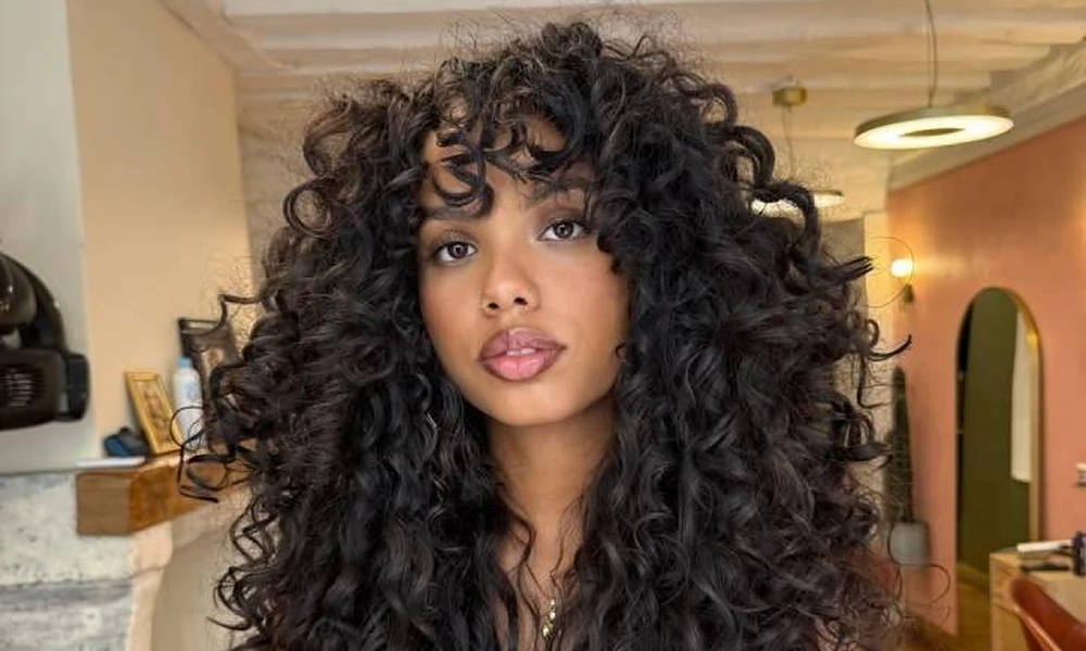 Dark brunette hair styled with voluminous face-framing fringe bangs and soft layers