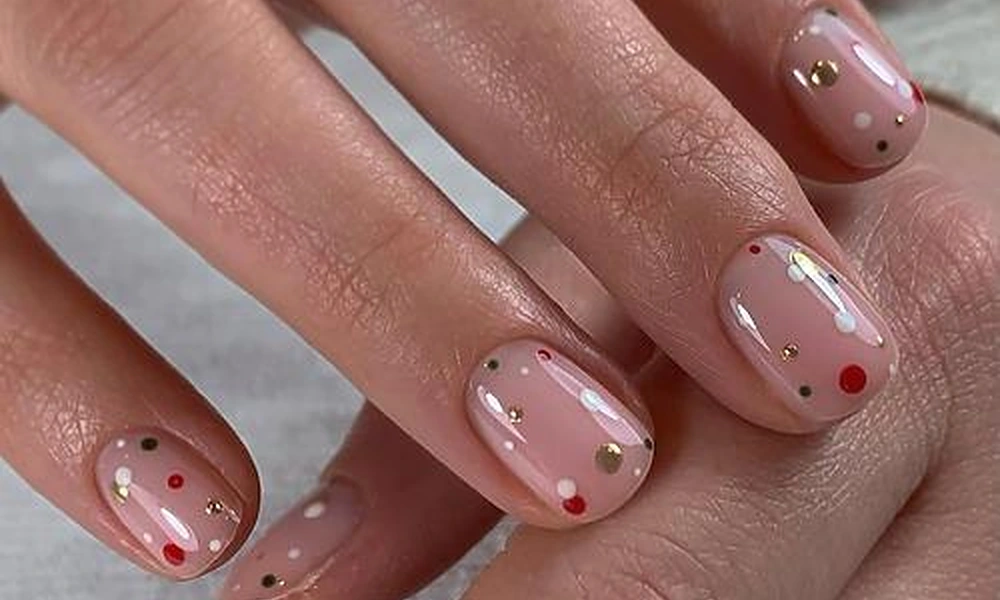 Subtle and clean minimalist Christmas nails on a sheer base decorated with tiny white stars