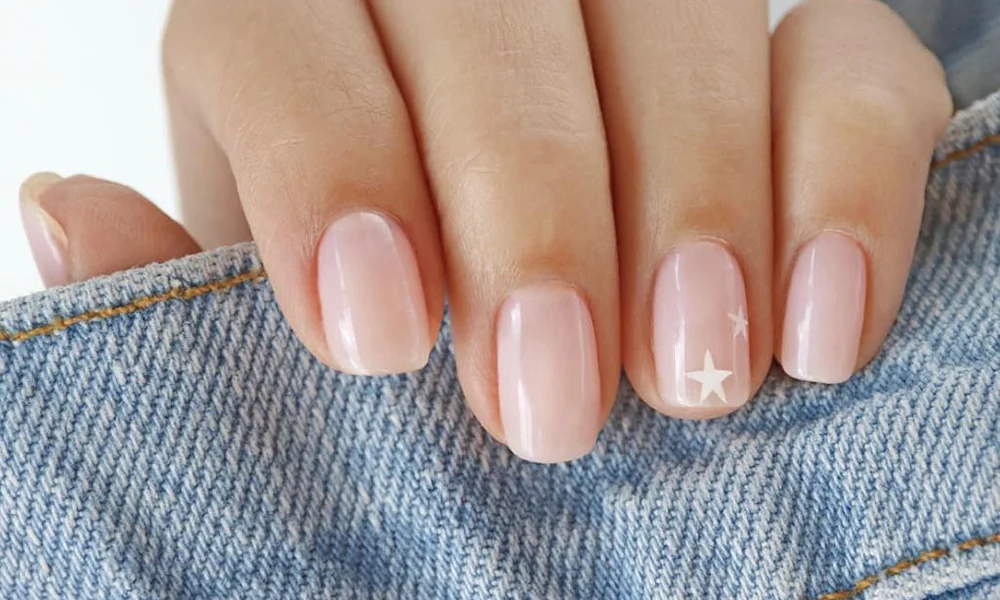 Subtle and clean minimalist winter manicure on a sheer base decorated with tiny white stars