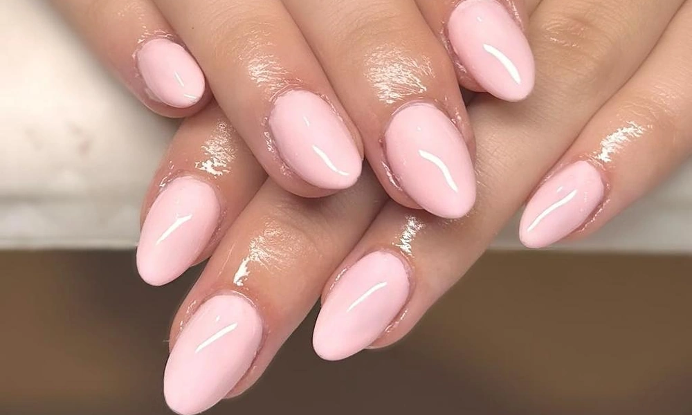 Glossy baby pink gel x nails styled in a smooth almond shape for a vibrant look