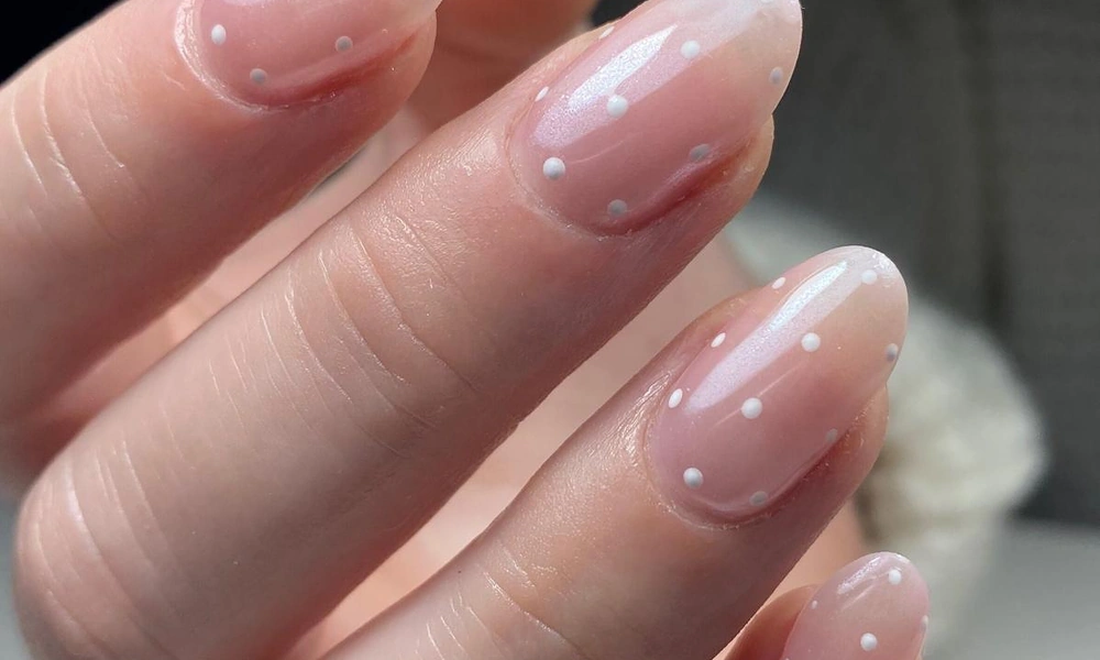 Translucent sheer pink gel polish decorated with fine white micro polka dots