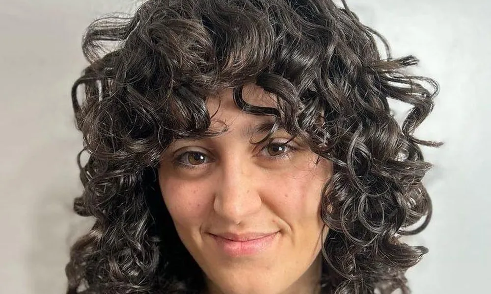 Shoulder-length textured locks cut into bouncy curls with matching fringe bangs